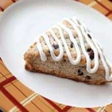 a slice of Simple Carrot Cake Scones in a white plate, drizzled with tangy cream cheese icing