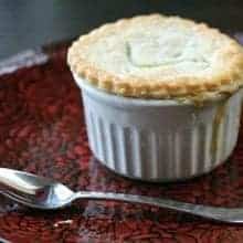 Mini Chicken Pot Pies in white ramekins on a red rose designed plate with spoon