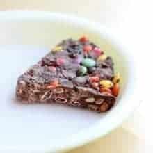 a slice of Leftover Halloween Candy Pie in a white shallow pie dish