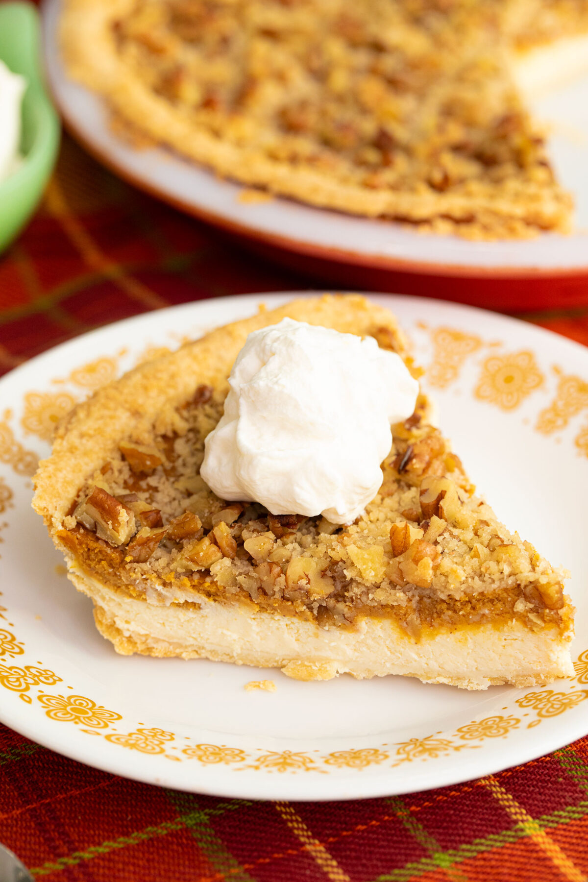 a slice of pumpkin paradise pie on a white plate with a dollop of whipped topping.