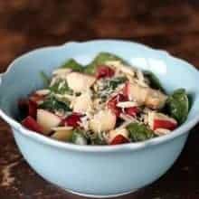 Close up of Apples N' Cherries Spinach Salad in a blue Pyrex bowl