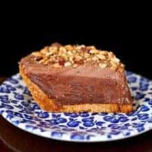 slice of hazelnut chocolate cream pie topped with crushed nuts in a small plate printed with blueberries