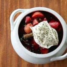 top down shot of chunky Ukrainian Borsch topped with sour cream and dill in a pot like white bowl