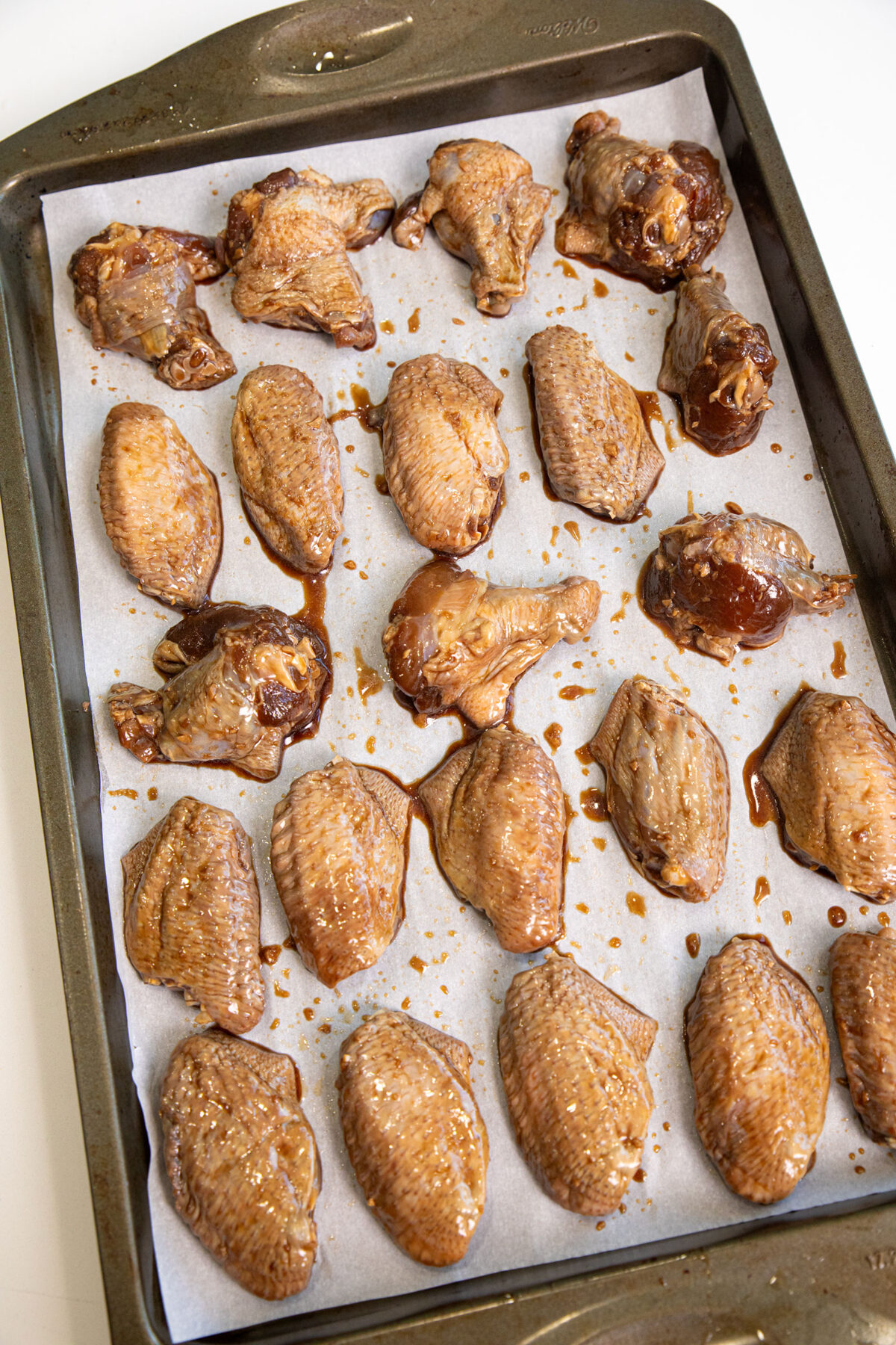 marinated raw chicken wings on a baking sheet