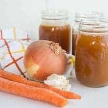 Crock Pot Bone Broth on Jars, Organic Carrots and Onion in kitchen cloth beside it