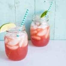 close up Sea Breeze Cocktail in a large mason glass jar topped with ice and garnished with a lime wedge