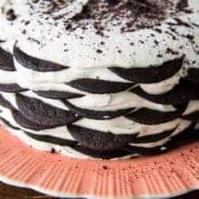 pink plate with Icebox Cake topped with whipped cream and sprinkles of leftover broken cookies