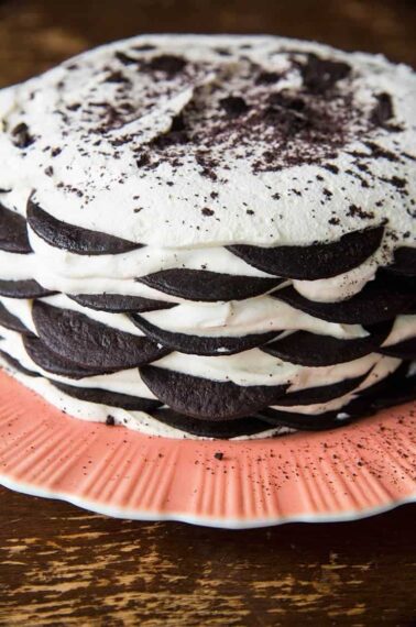 pink plate with Icebox Cake topped with whipped cream and sprinkles of leftover broken cookies