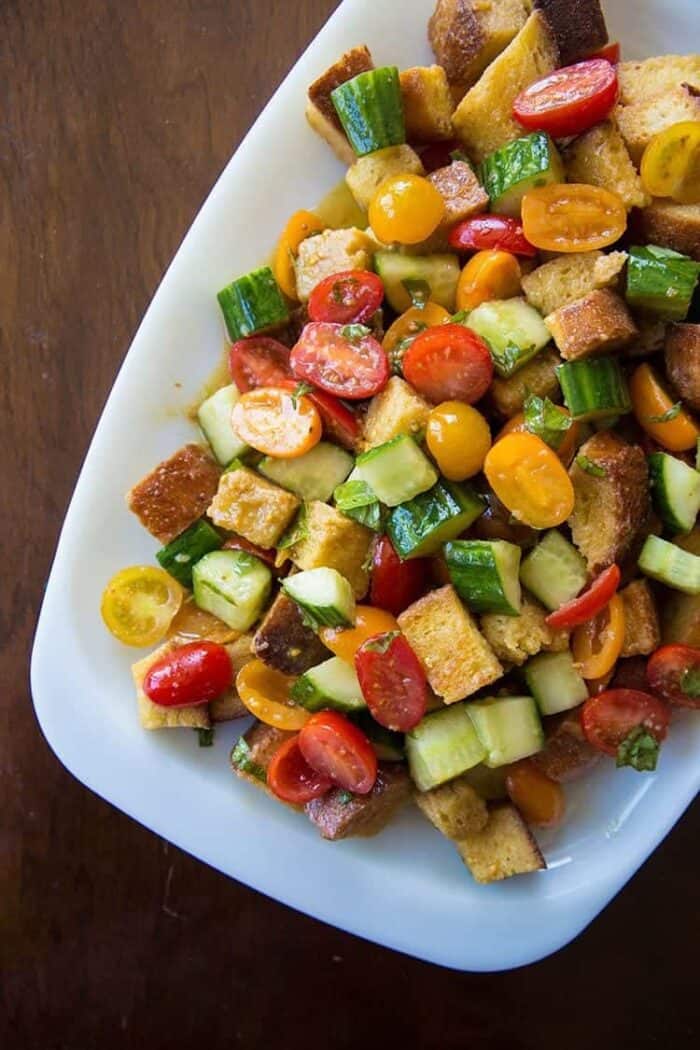 A plate of Summer Panzanella Salad with cherry tomatoes, cucumbers and a basil