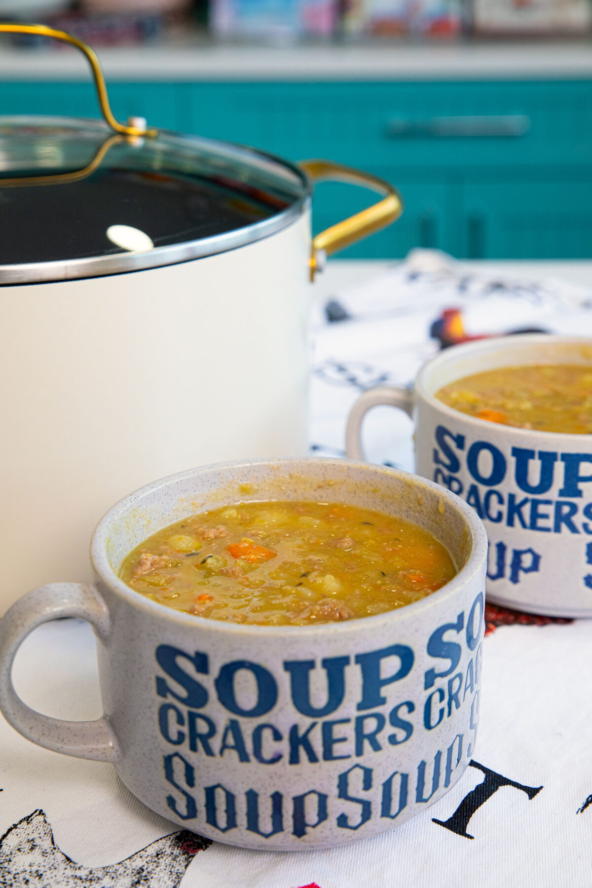 A white pot with split pea ground beef soup and a bowl of soup