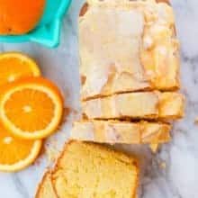 Top down shot of Sliced Orange Loaf Cake Topped with Orange Icing Glaze, Sliced Orange on the side