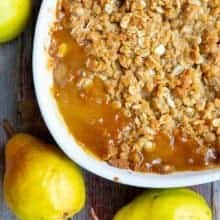 close up oval white plate with Pear Crisp, 3 pieces Yellow Bartlett Pears on background