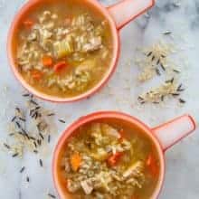 top down shot of Turkey Carcass Soup in a marble table with some wild rice mix