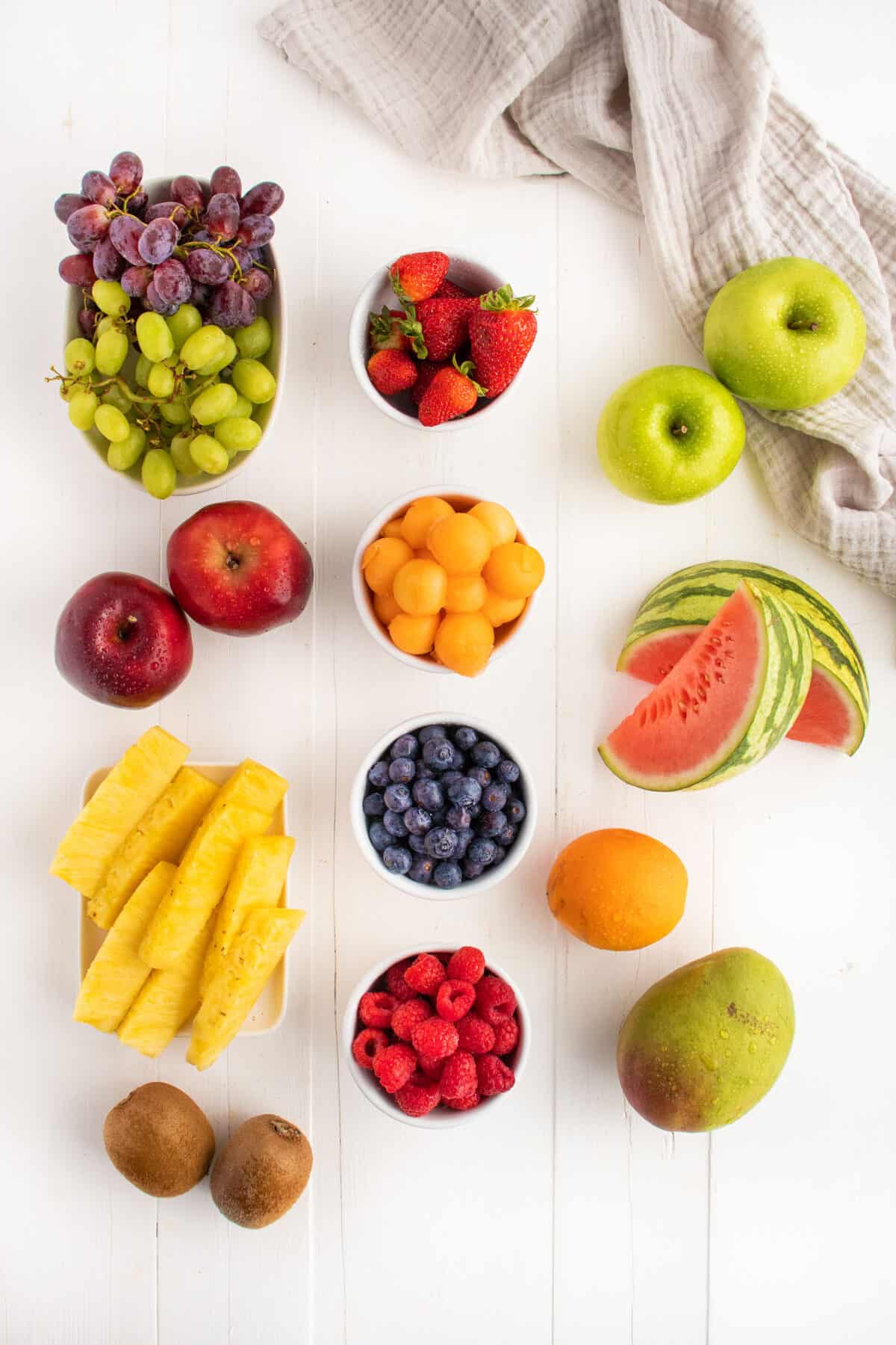 types of fruit for a fruit platter, raspberries, blueberries, grapes, apples, watermelon, oranges, mangoes, pineapple and kiwis 