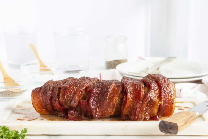 bacon wrapped pork loin on a white plate un cut