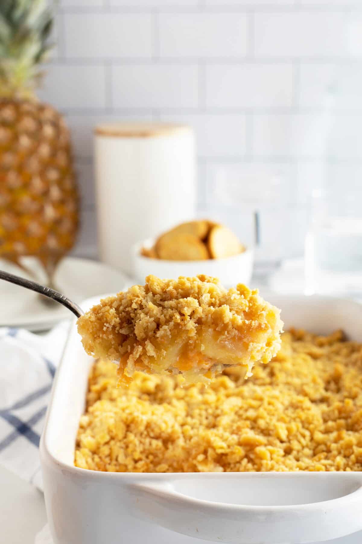 Pineapple casserole on a large spoon lifed out of the casserole dish