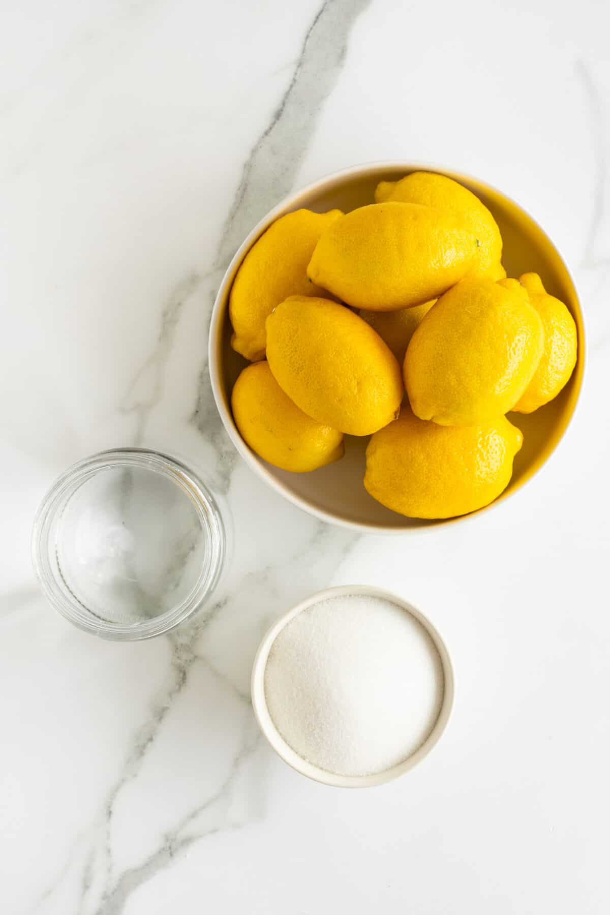 fresh lemonade ingredients, lemons sugar and water in separate bowls