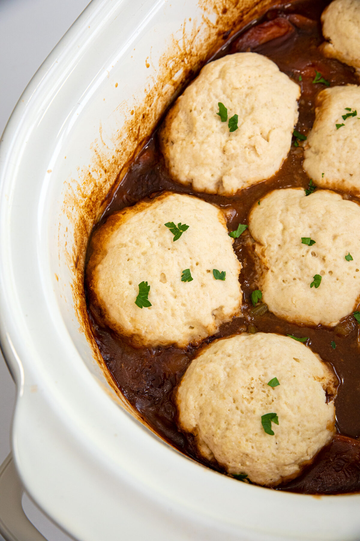 Biscuit dumplings with parsley sprinkled on top in a slow cooker