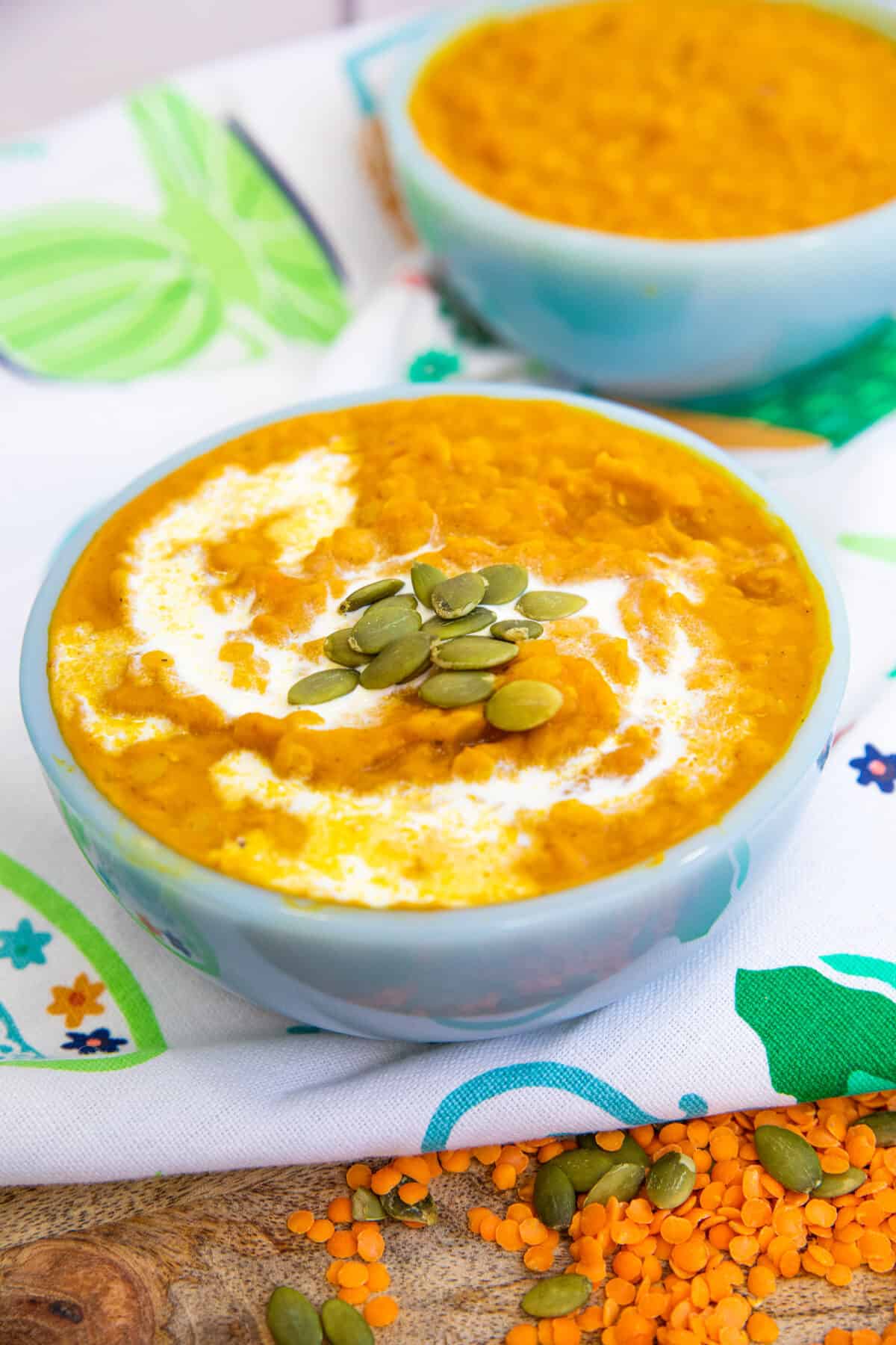 Pumpkin lentil soup in a blue bowl with pumpkin seeds on top