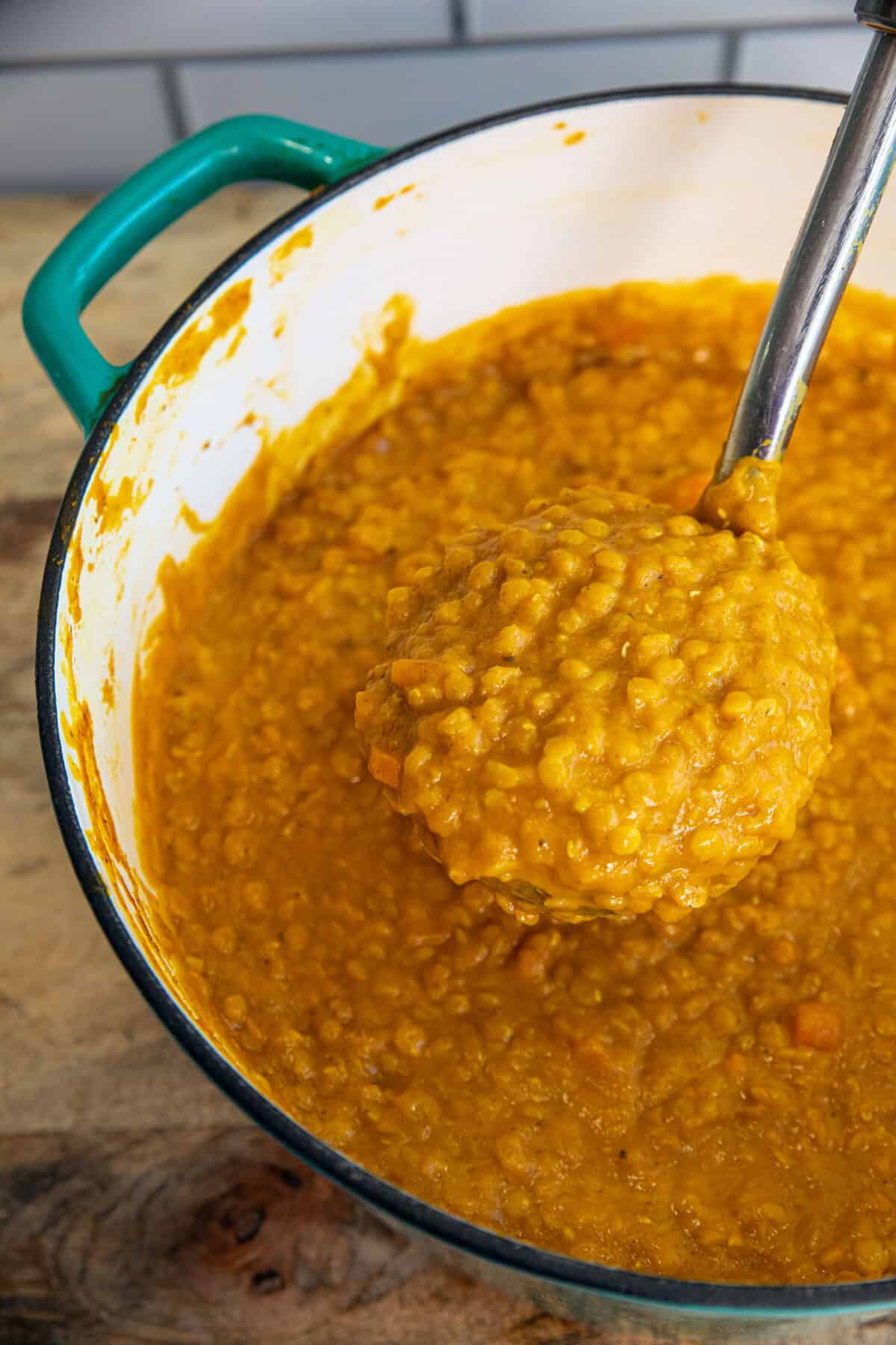 pumpkin lentil soup in a large pot with a ladle full