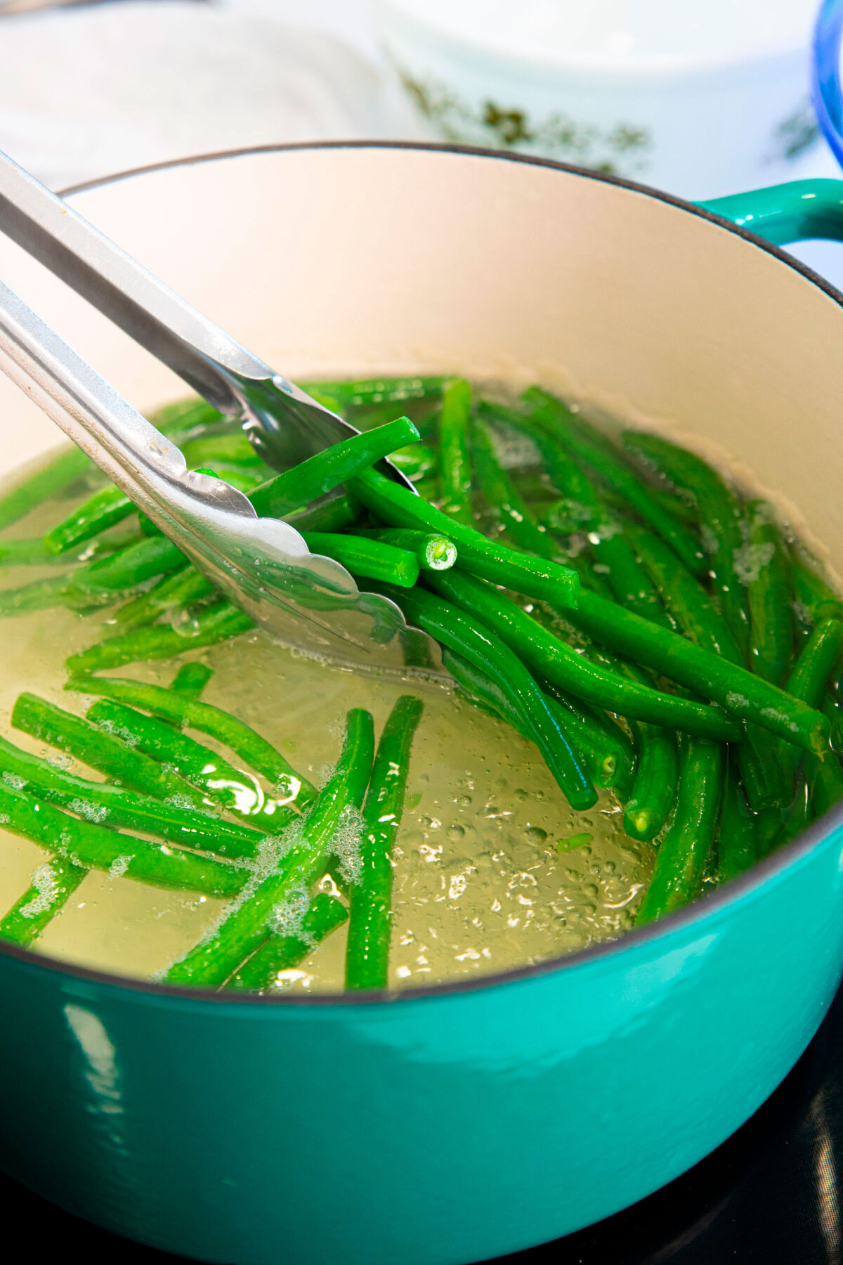 Green beans in a pair of tongs over boiling water