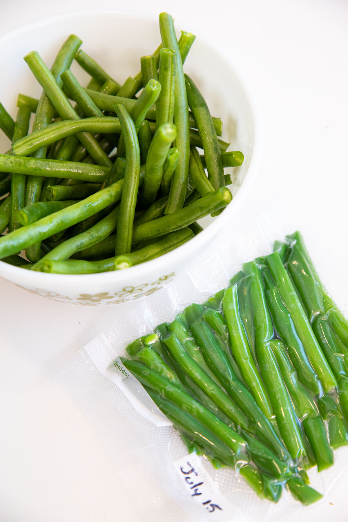 blanched green beans in a bowl and a freezer bag of beans