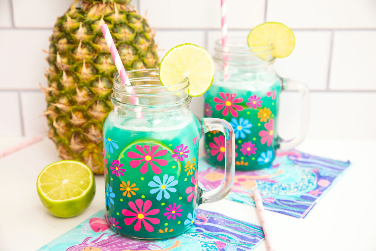 Mermaid Water cocktail on a counter top with a pineapple in the background.