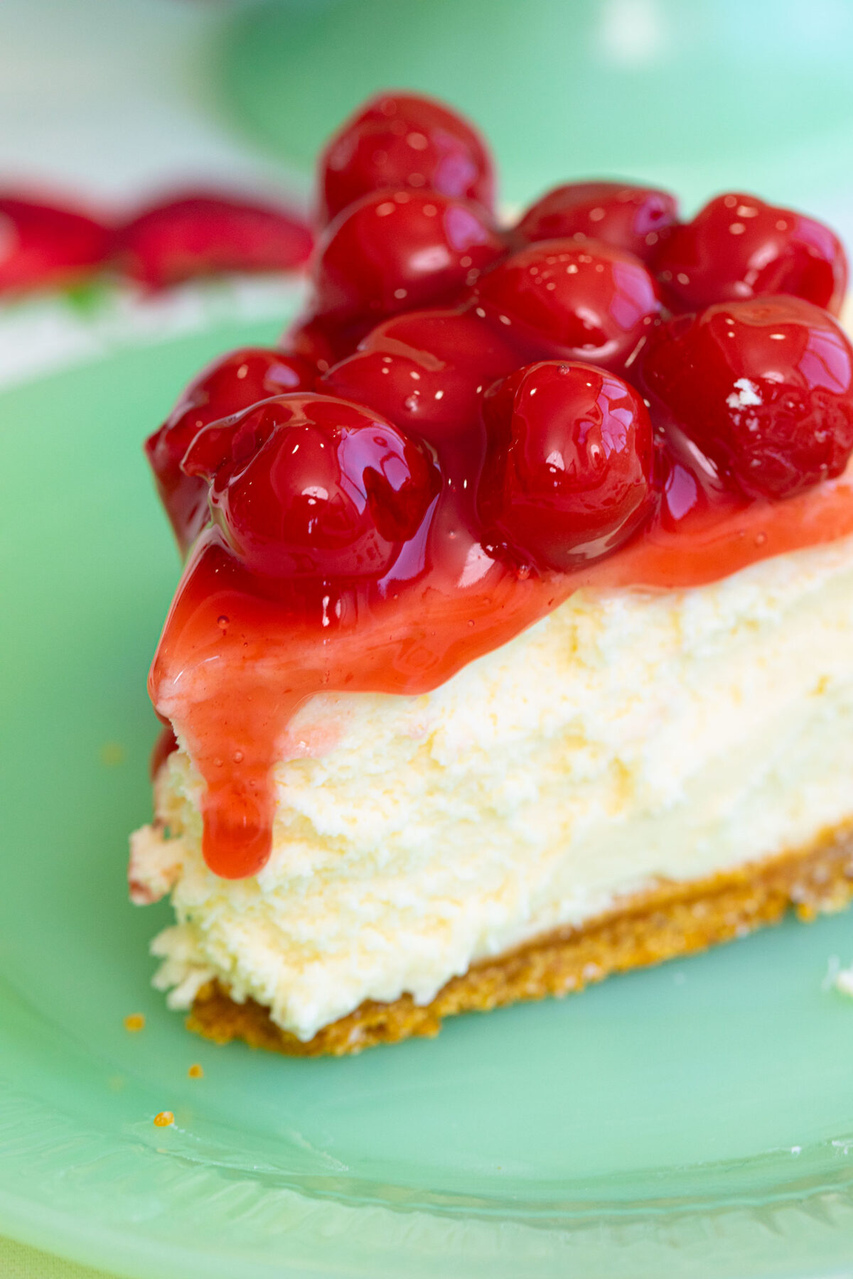 A closeup photo of a slice of Philadelphia cheesecake topped with cherry pie filling