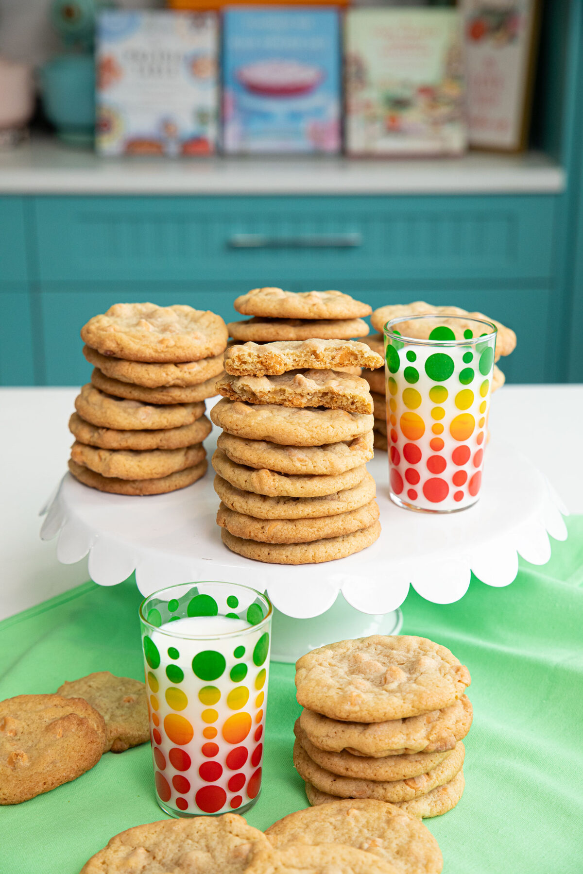 butterscotch cookies stacked in piles of 7 with glasses of milk beside them.