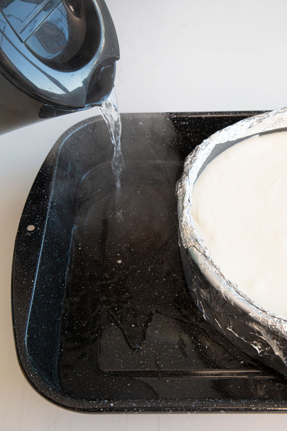 pouring boiler water in a roaster for a cheesecake water bath