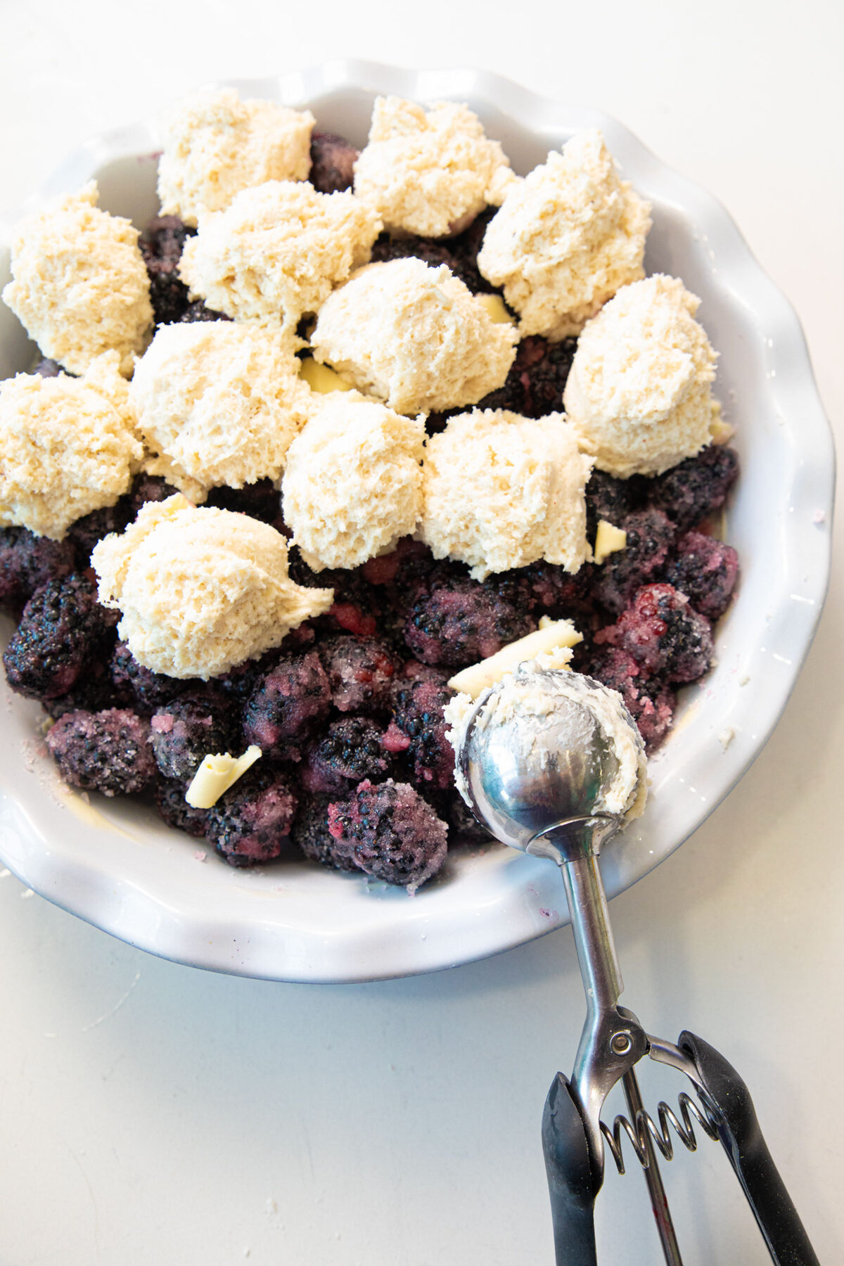 scooping the topping onto the blackberries in pie plate