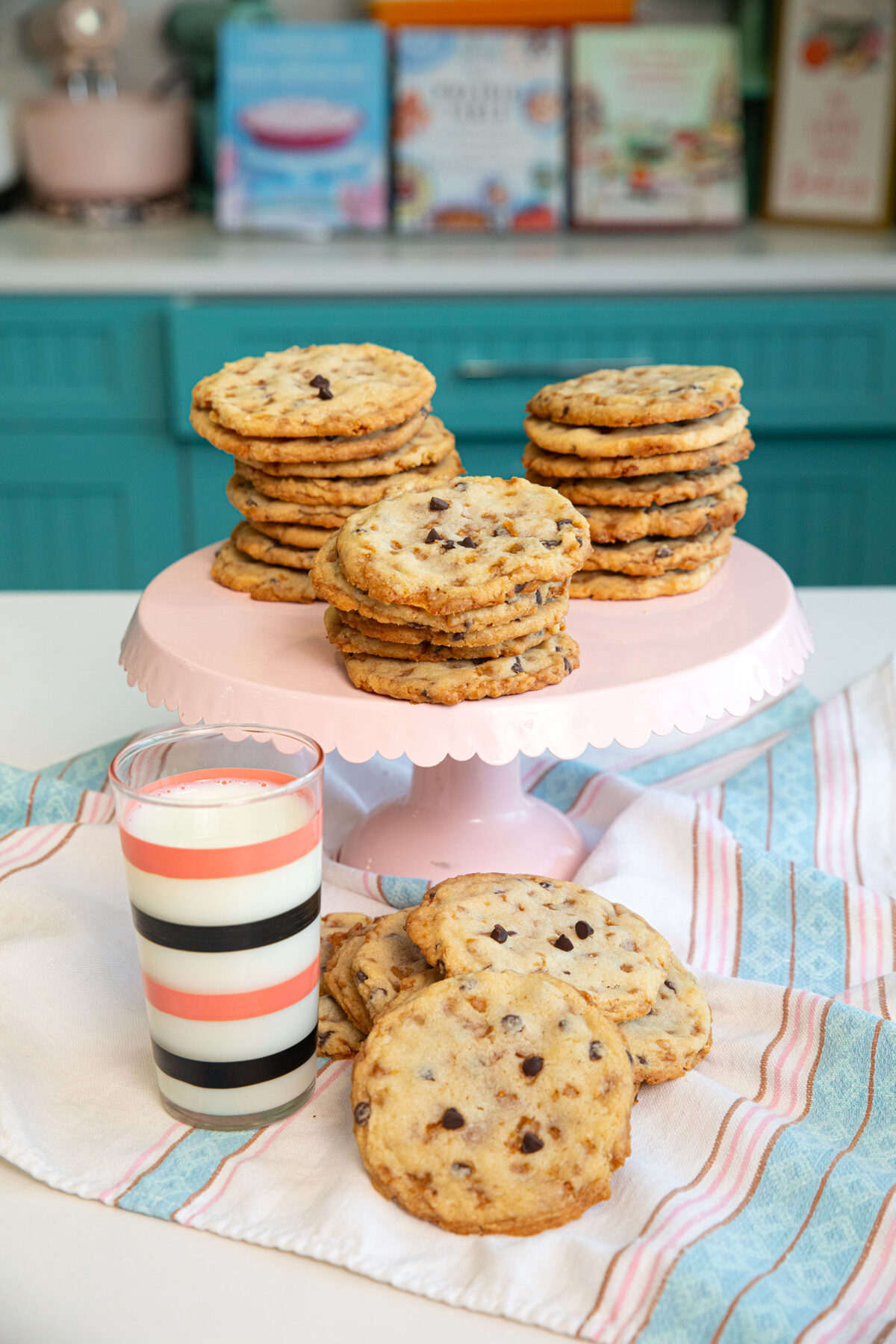 toffee crunch cookies on a large pink platter with a glass of milk