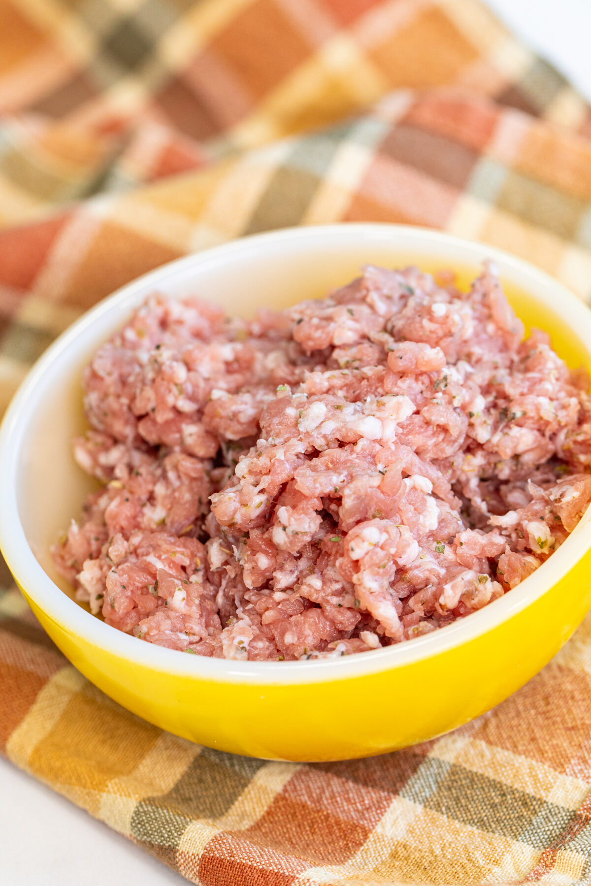 raw Italian seasoned ground pork in a yellow bowl